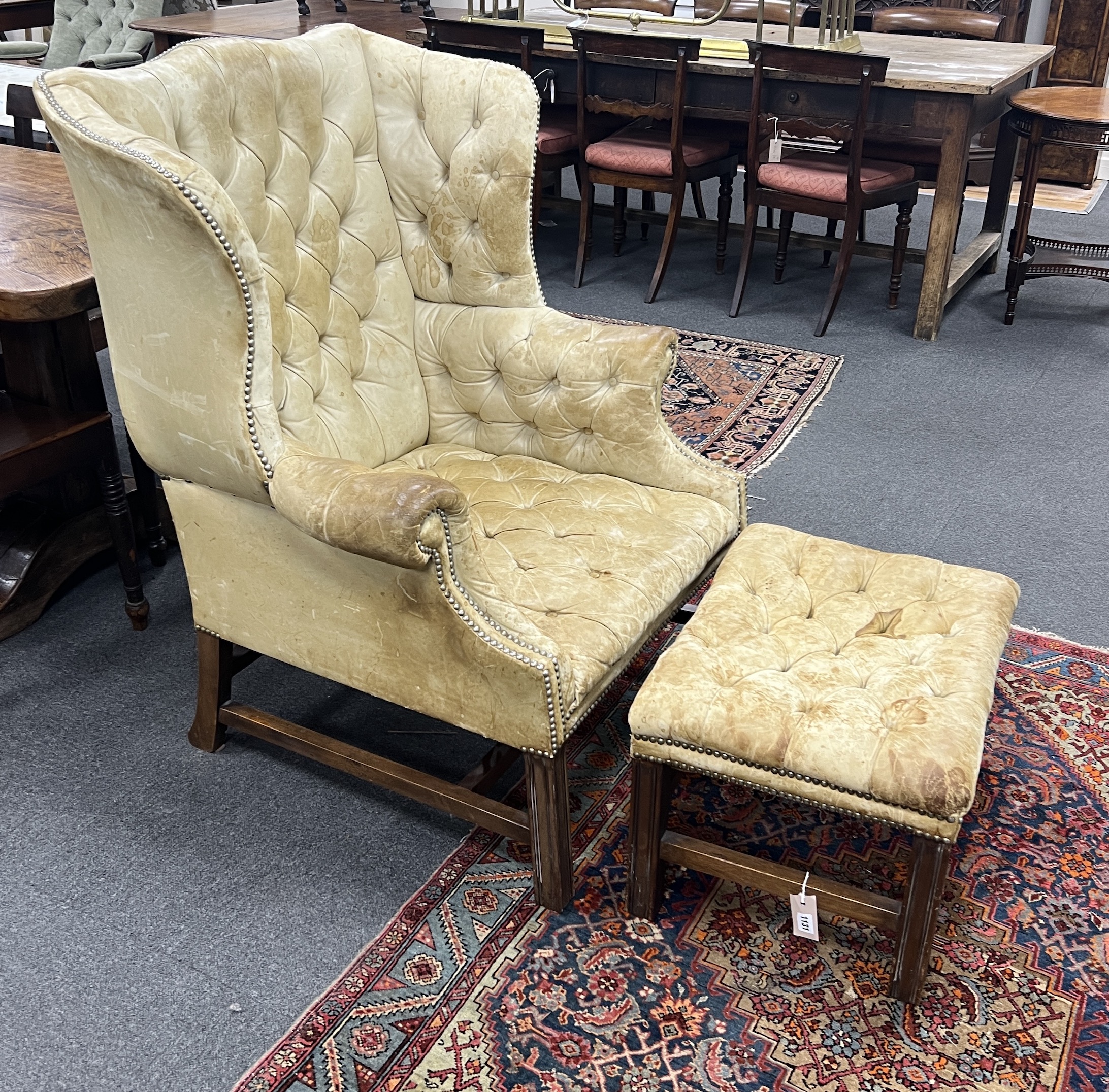 A George III style mahogany and buttoned leather wing armchair, width 80cm, depth 75cm, height 110cm with footstool